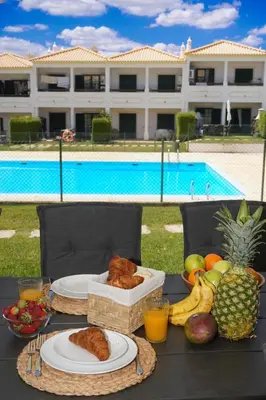 a table with plates of food and fruit next to a pool at Casa Santos in Albufeira