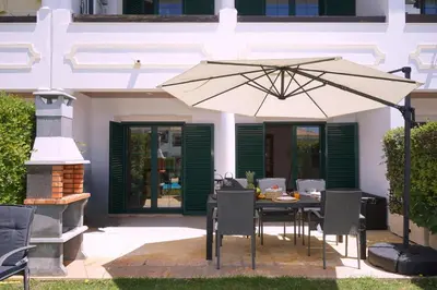 a table with an umbrella in front of a house at Casa Santos in Albufeira