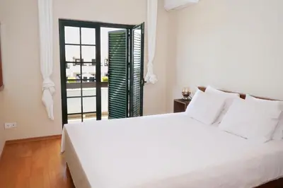 a bedroom with a large white bed and a window at Casa Santos in Albufeira