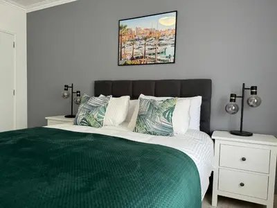 a bedroom with a large bed with a green comforter at Princess Retreat Beautiful Modern Aprt 2 min walk from Quarteira Beach in Quarteira