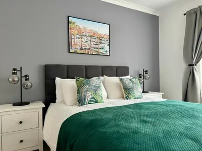 a bedroom with a bed with a green comforter at Princess Retreat Beautiful Modern Aprt 2 min walk from Quarteira Beach in Quarteira