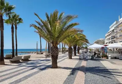 a beach with palm trees and chairs and the ocean at Princess Retreat Beautiful Modern Aprt 2 min walk from Quarteira Beach in Quarteira