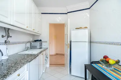 a kitchen with white cabinets and a white refrigerator at VILAMOURA Two Bedroom Near Praia Falésia in Quarteira