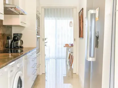 a kitchen with white cabinets and a door leading to a table at Serenity 06 House by Stay ici Algarve Holiday Rental in Albufeira