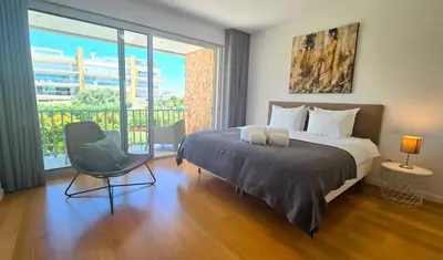 a bedroom with a bed and a chair and a window at Segolene Design in Albufeira