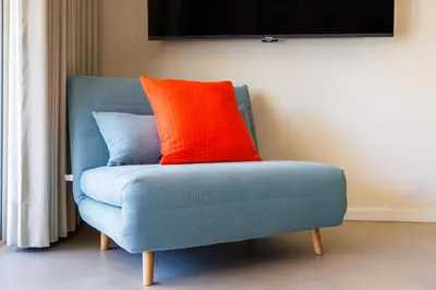 a blue chair with an orange pillow on it at Vilamoura Dream House QR2 in Quarteira