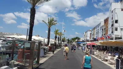 a group of people walking down a street with palm trees at Vilamoura Dream House QR2 in Quarteira