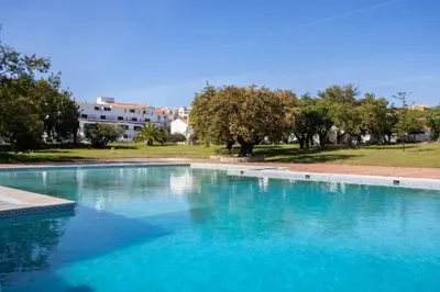 a large pool of blue water with trees in the background at Cosy apartment in Albufeira, OURA ST in Albufeira