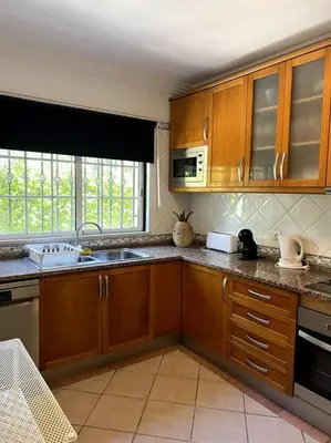 a kitchen with wooden cabinets and a sink at Moradia Almorávia in Olhos de Água