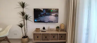 a living room with a tv on a wall at Casa de Praia em São Rafael in Albufeira