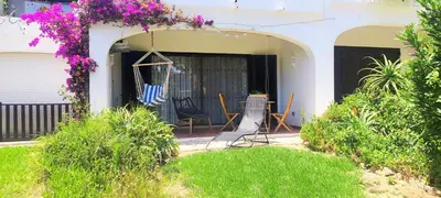 a patio with chairs and a hammock on a house at Casa de Praia em São Rafael in Albufeira
