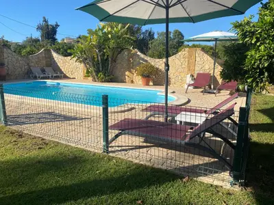 a fence with chairs and an umbrella next to a pool at Villa Albufeira 1 à 6 personnes in Guia
