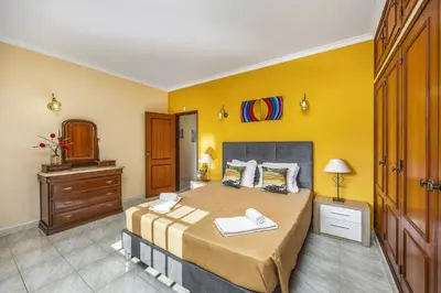a bedroom with a bed and a yellow wall at Villa Vista Mar by Villa Plus in Terras Novas