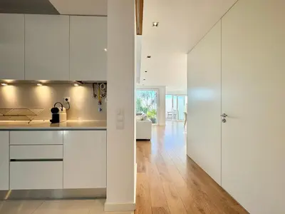 a kitchen with white cabinets and a wooden floor at Narciso Townhouse in Faro