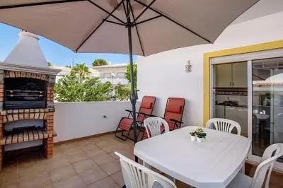 a white table and chairs with an umbrella on a patio at V2 a 400 m da Praia da Falésia in Albufeira