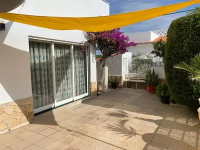a patio with a yellow umbrella on a house at Villa Cristipaulo in Praia de Faro