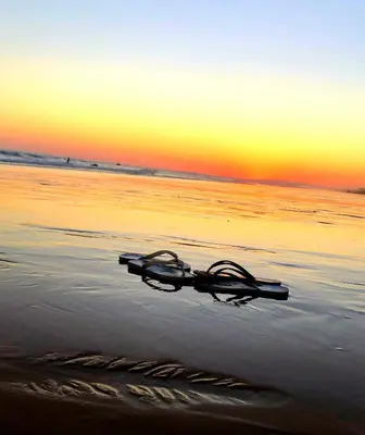a pair of glasses laying on the beach at sunset at Villa Cristipaulo in Praia de Faro