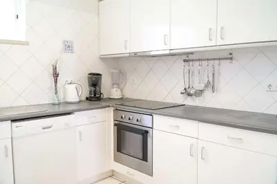 a kitchen with white cabinets and a stove top oven at Villa Lychee in Guia