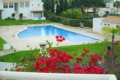 a swimming pool in a yard with red flowers at Villa Lychee in Guia