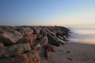a group of rocks on a beach near the water at Vacation Apartment in Quarteira in Cavacos