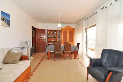 a living room with a table and a couch at Vacation Apartment in Quarteira in Cavacos