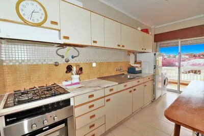 a kitchen with white cabinets and a clock on the wall at Vacation Apartment in Quarteira in Cavacos
