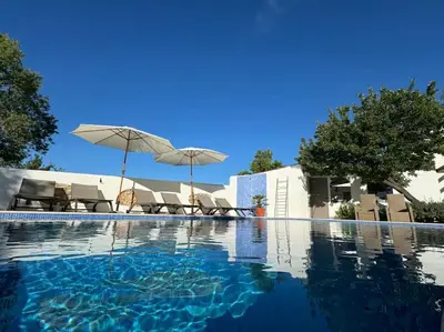 a swimming pool with chairs and umbrellas next to a building at Casa Nova Vida in Paderne