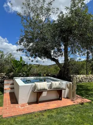 a hot tub with a bench and a tree at Casa Nova Vida in Paderne