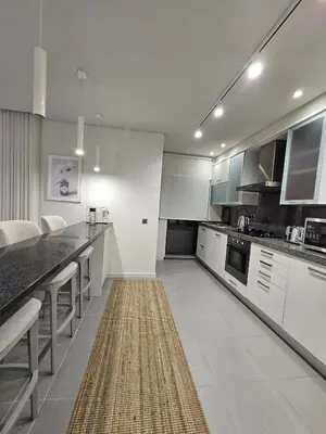 a kitchen with white cabinets and a rug on the floor at Paraíso Forte Novo in Quarteira