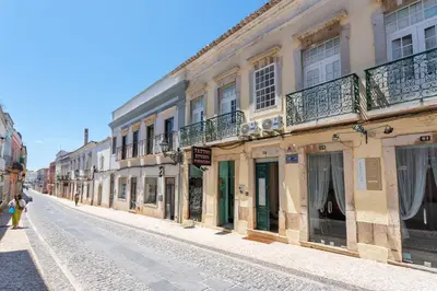 a street with buildings and people walking down the street at Blife Alicya private rooms in Faro