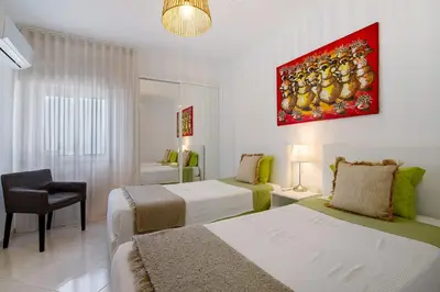 a hotel room with two beds and a chair at T1 com vista mar in Quarteira