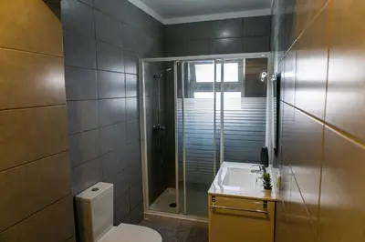 a bathroom with a shower and a toilet and a sink at Aconchego de quartos no centro de Faro in Faro