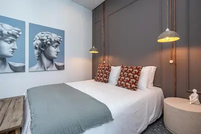 a bedroom with a large white bed with a bust at Dona Simone Boutique Suites & Studios - by @ rita's place in Faro