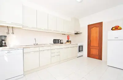 a white kitchen with white cabinets and a refrigerator at Villa Ibiza by Algarve Vacation in Guia