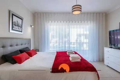 a bedroom with a bed with a red blanket and a tv at #226 Vila LII by Home Holidays in Albufeira