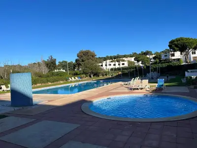 a large swimming pool with chairs at Pe do Lago cosy apartment in Quarteira