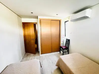 a bedroom with two beds and a wooden door at Pe do Lago cosy apartment in Quarteira