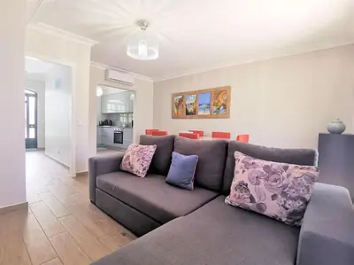 a living room with a gray couch with purple pillows at Casa Tulipa Ferias - Vilamoura in Quarteira