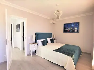 a white bedroom with a large bed and a table at Casa Tulipa Ferias - Vilamoura in Quarteira