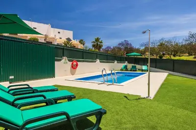 a swimming pool with green chairs in a backyard at Villa Krishan Albufeira - Private Pool in Albufeira