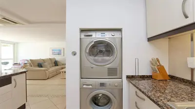 a kitchen with a washing machine and a living room at Marina parque CD 68 - Cleverdetails - private pool, few steps to the marina in Vilamoura