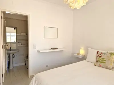 a white bedroom with a bed and a sink at Ancão beach duplex with private garden in Almancil