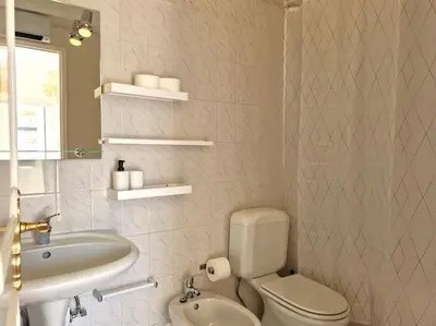 a bathroom with a white toilet and a sink at Ancão beach duplex with private garden in Almancil