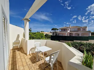 a patio with a table and chairs and a house at Ancão beach duplex with private garden in Almancil