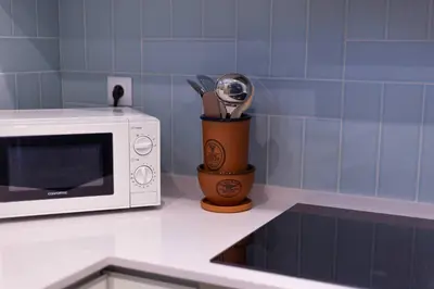 a kitchen counter with a microwave and a cup of kitchen utensils at Villa Golden Falésia by HelloVacations in Albufeira