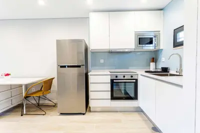 a kitchen with white cabinets and a stainless steel refrigerator at Villa Serenity Falésia by HelloVacations in Albufeira