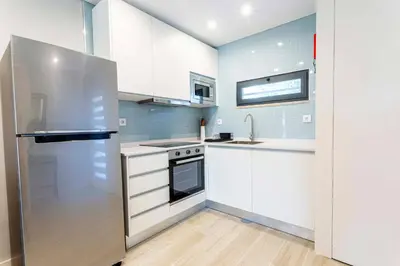 a kitchen with white cabinets and a stainless steel refrigerator at Villa Serenity Falésia by HelloVacations in Albufeira