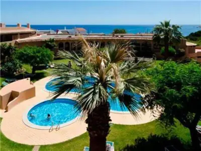 a palm tree in front of a swimming pool at Perfect ApartHotel 1 Bedroom in Olhos de Água