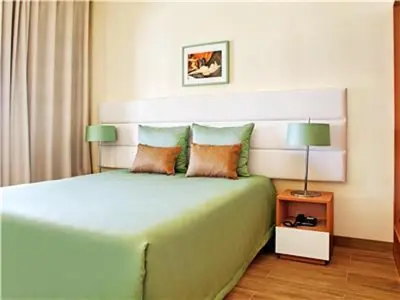 a bedroom with a large green bed with two pillows at Perfect ApartHotel Apartments 1 Bedroom in Albufeira
