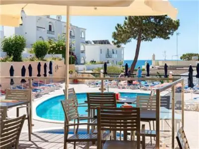 a table with chairs and an umbrella next to a pool at Superb Apartments 2 Bedroom in Olhos de Água